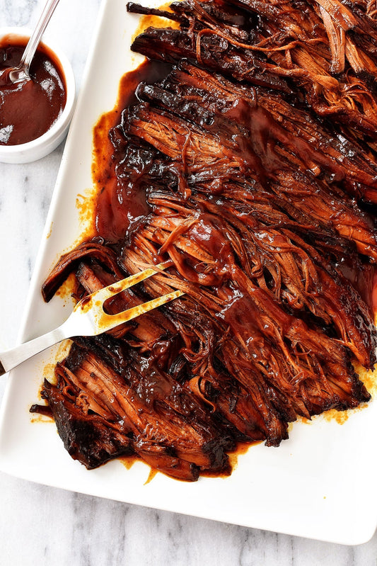 Slow cooker BBQ beef brisket with tender slices in barbecue sauce.