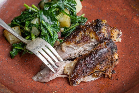 Slow roasted goat shoulder seasoned with a spicy dry rub, showcasing tender meat and crispy edges