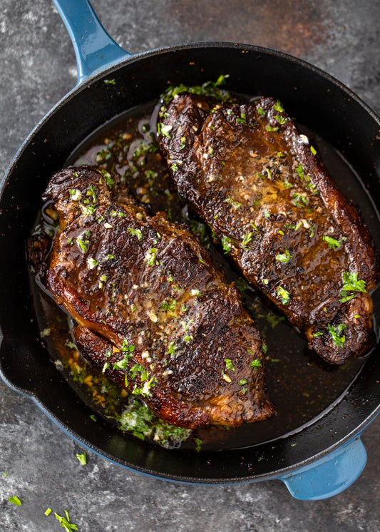 Pan seared chuck arm steak topped with garlic herb butter, showcasing a golden brown crust.