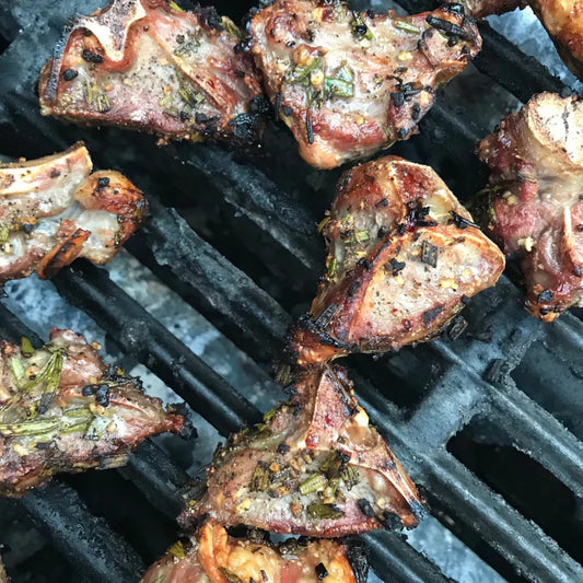 Grilled goat rib chops seasoned with rosemary and garlic, showcasing a perfect sear and tender meat