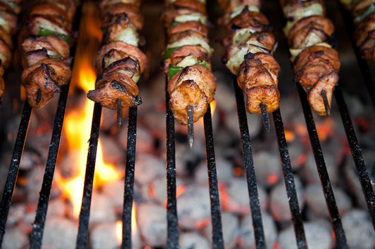 Grilled beef heart skewers with vegetables, showcasing tender, charred meat.