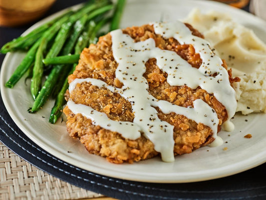Country fried steak with creamy gravy and a side of mashed potatoes.