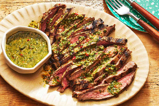 Grilled flank steak topped with chimichurri sauce and fresh herbs