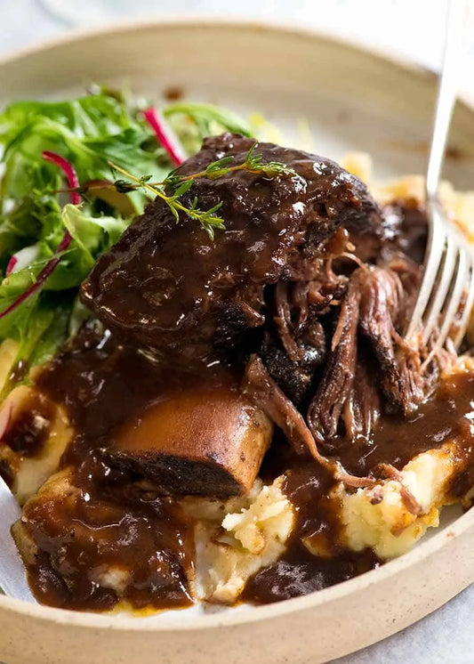 Braised beef short ribs in red wine sauce served over mashed potatoes with a side salad