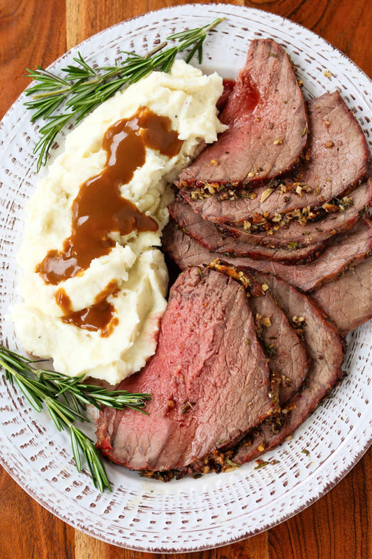 Rustic garlic and herb crusted chuck arm roast, slice and plated with a side of mashed potatoes and gravy.