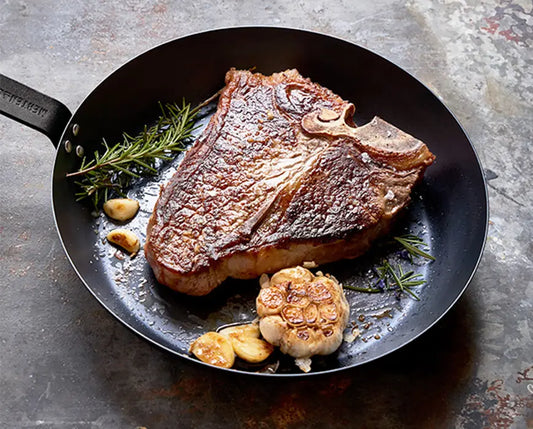 Perfectly seared porterhouse steak with grill marks, shown in a cast iron skillet, ready to be served.